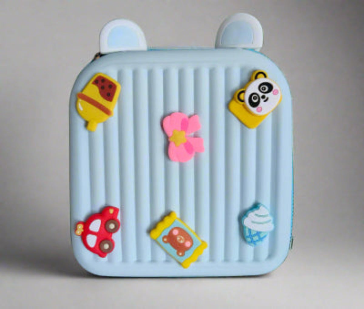 Children's toy suitcase with cartoon character stickers on a grass background