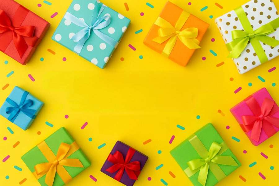 Colorful gift boxes with ribbons on a yellow background with colorful confetti